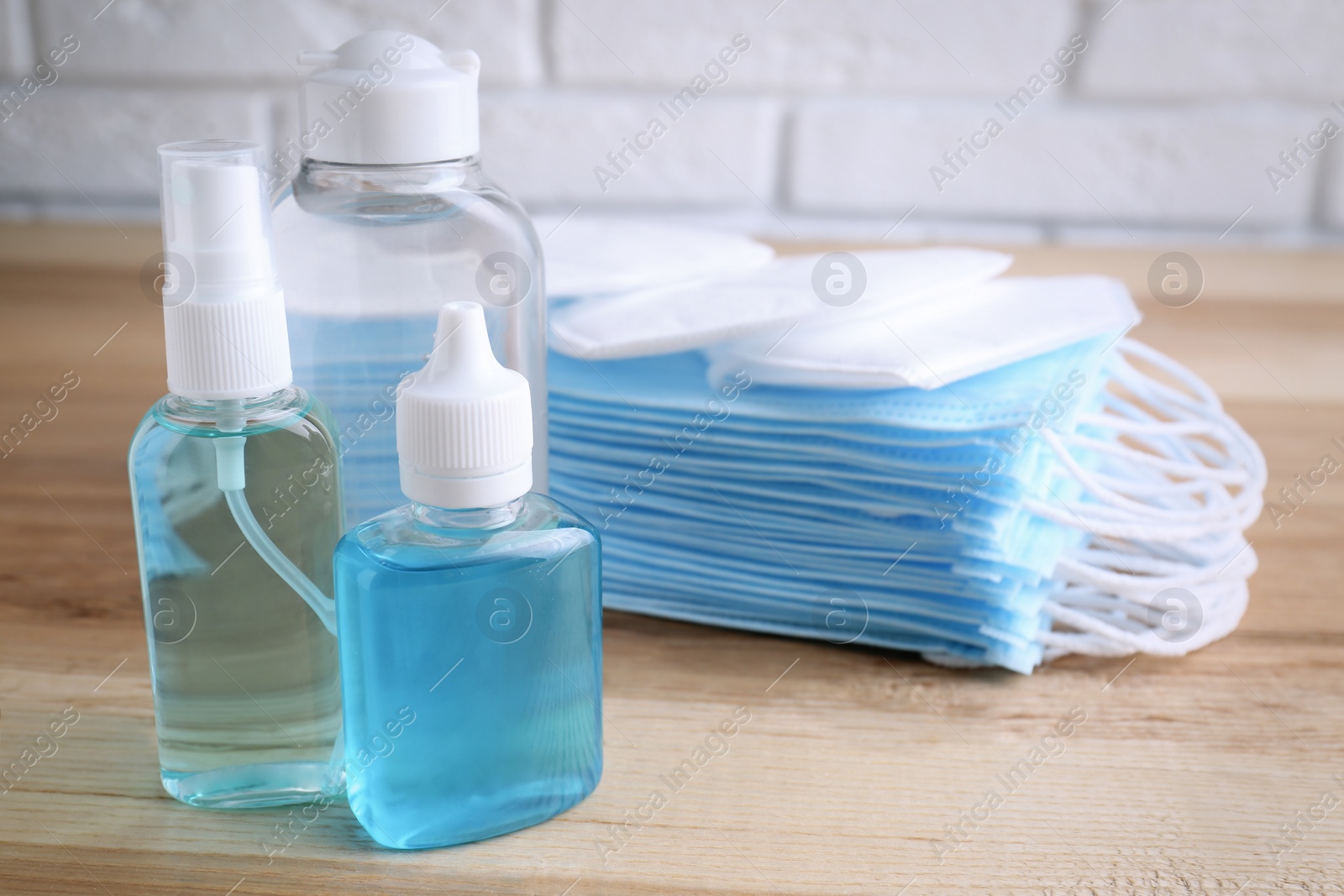 Photo of Hand sanitizers and respiratory masks on wooden table. Protective essentials during COVID-19 pandemic