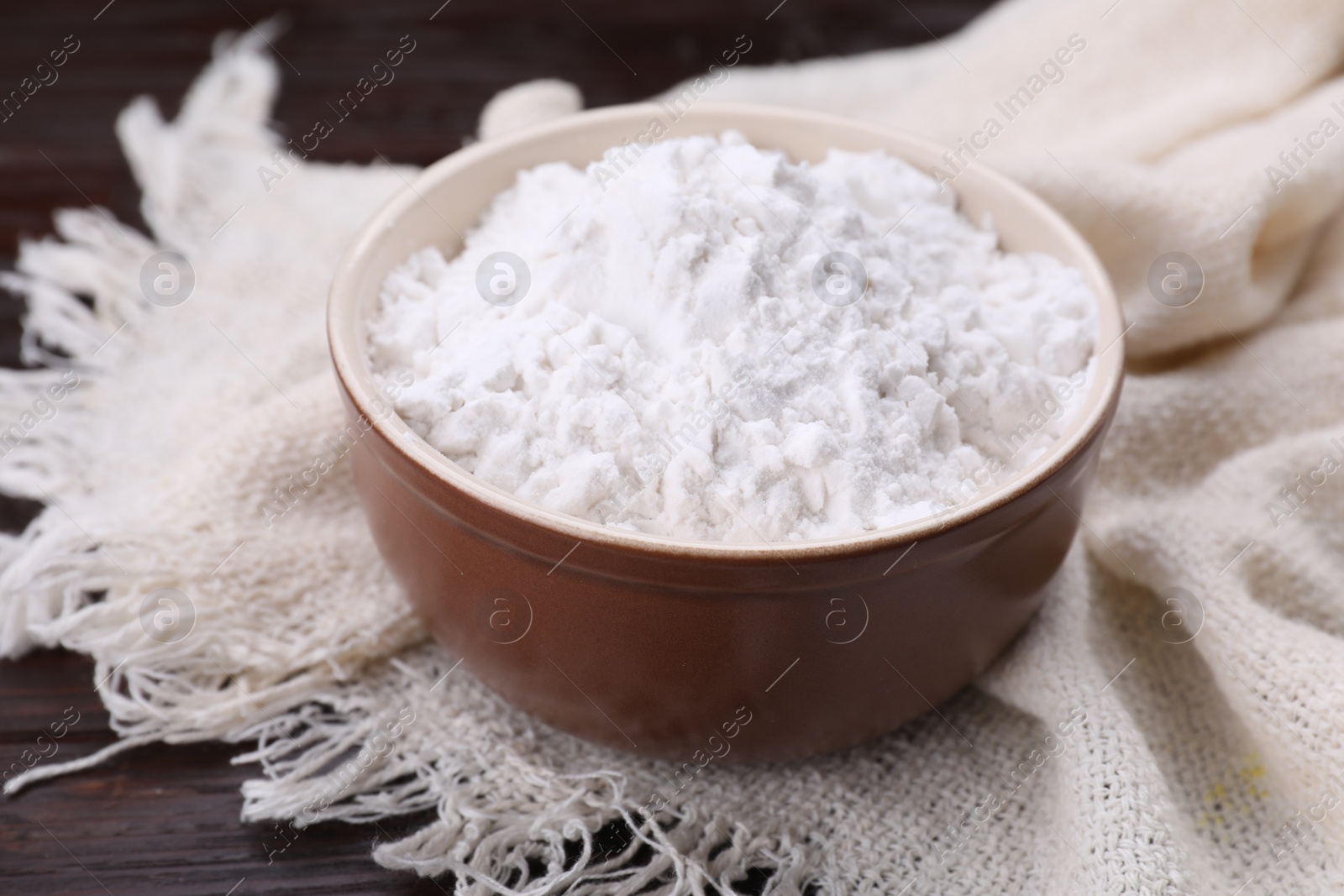 Photo of Starch in bowl on wooden table, closeup