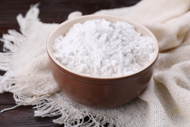 Photo of Starch in bowl on wooden table, closeup