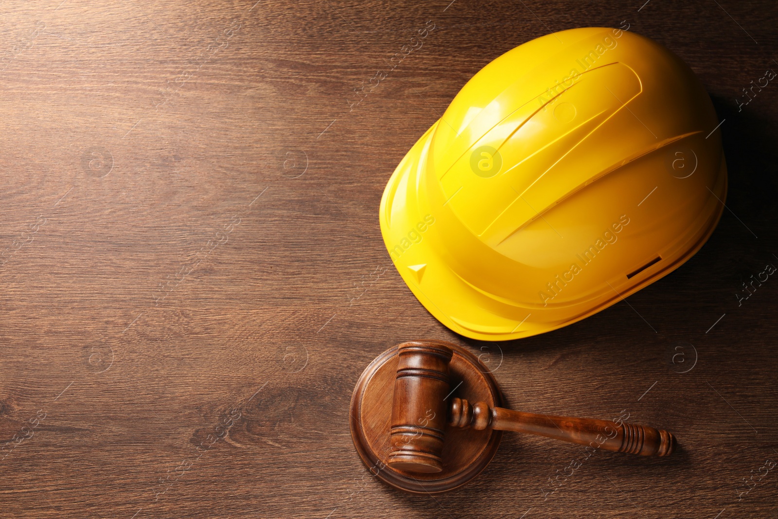 Photo of Law concept. Gavel and yellow hard hat on wooden table, top view. Space for text