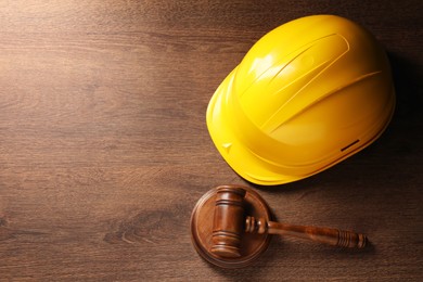 Photo of Law concept. Gavel and yellow hard hat on wooden table, top view. Space for text