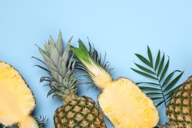 Whole and cut ripe pineapples on light blue background, flat lay. Space for text