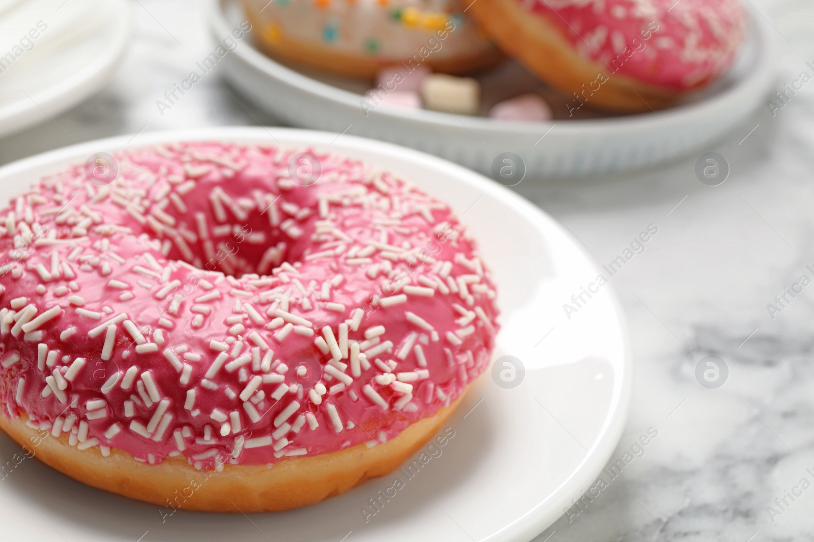 Photo of Yummy donut with sprinkles on white marble table, closeup