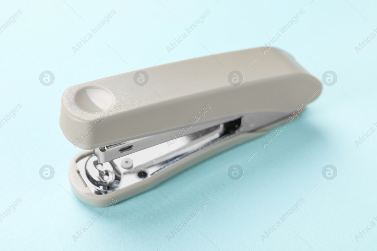 Photo of Beige stapler on light blue background, closeup