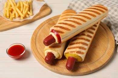 Photo of Delicious french hot dogs, fries and dip sauce on white wooden table