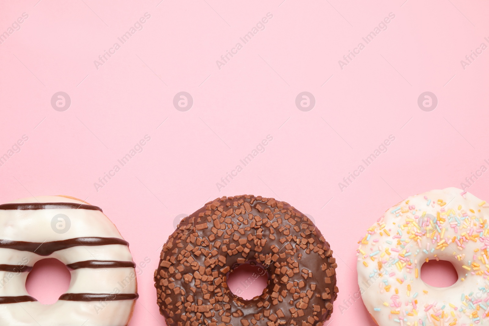 Photo of Delicious glazed donuts on pink background, flat lay. Space for text