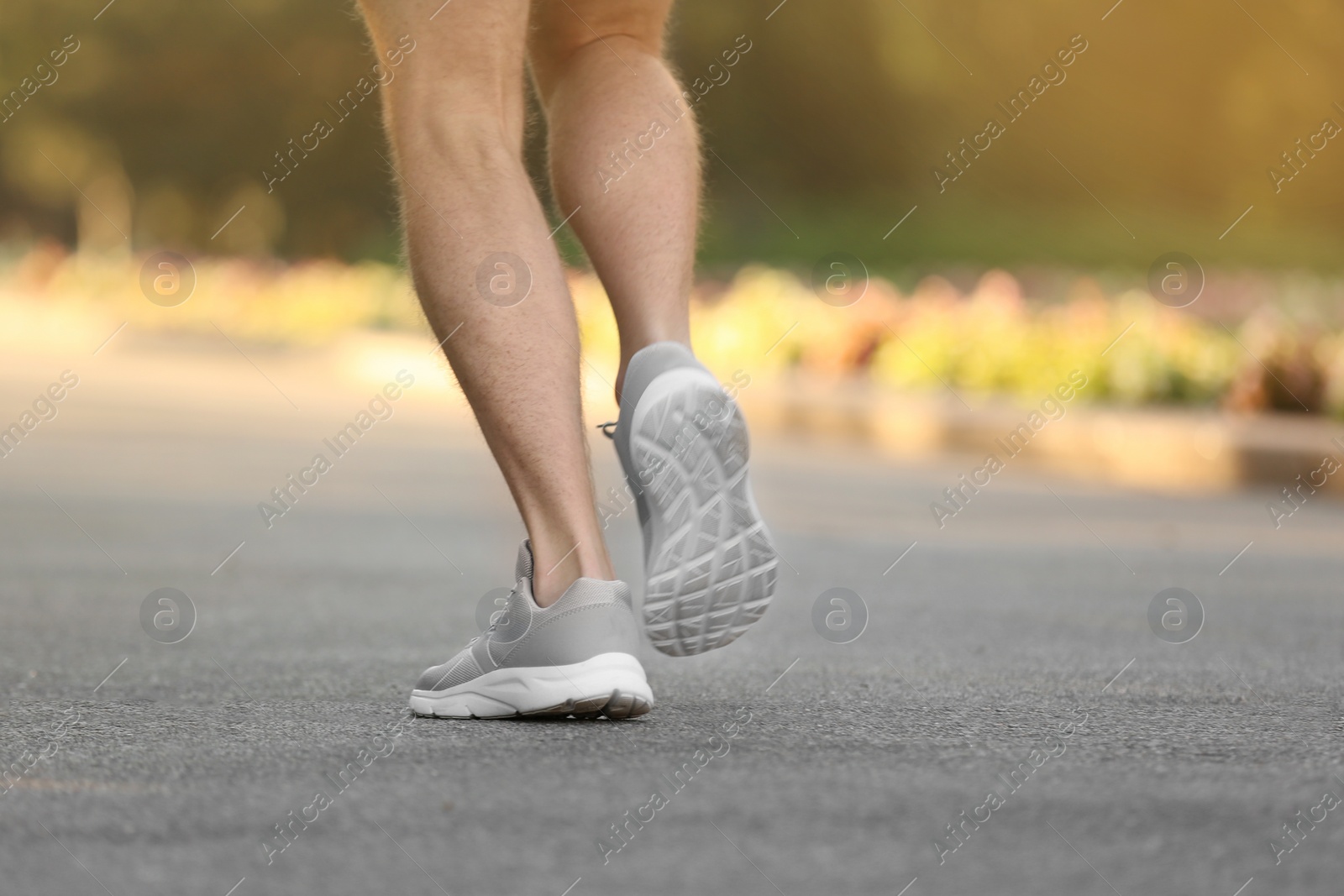 Photo of Young man running in park, focus on legs