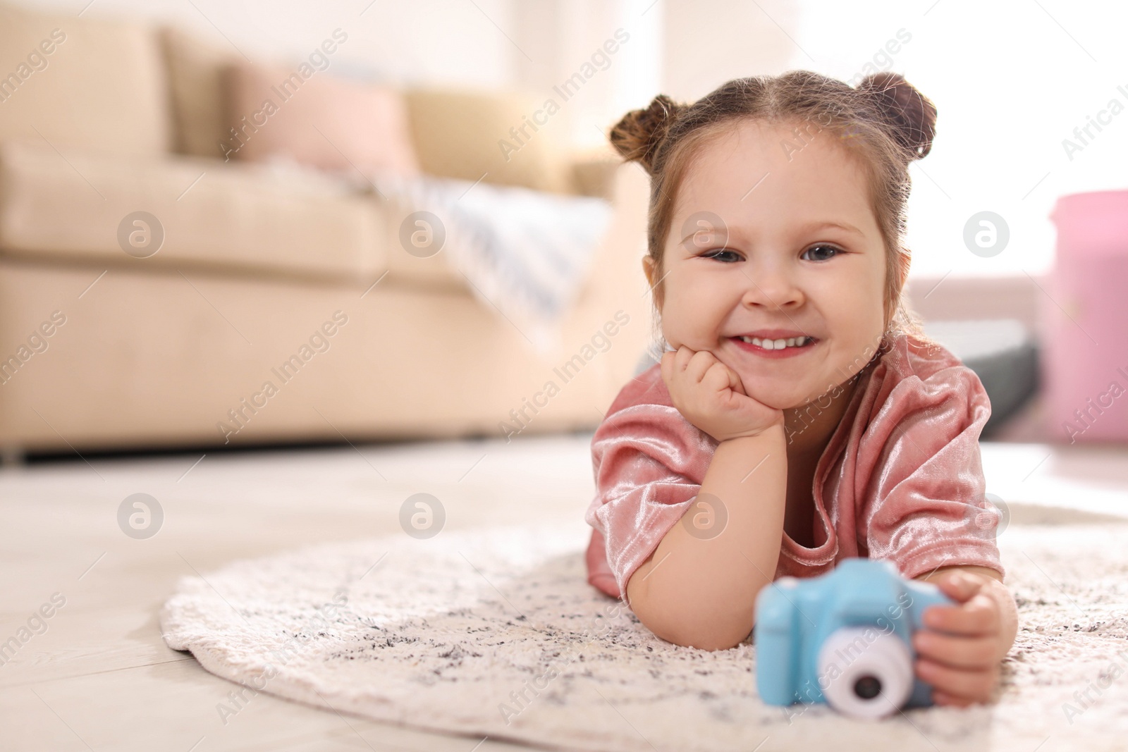 Photo of Little photographer with toy camera on floor at home. Space for text