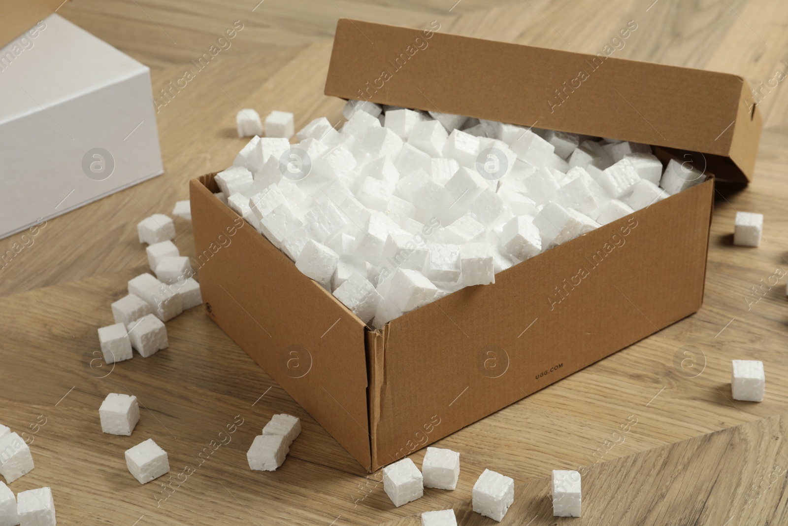 Photo of Cardboard box and styrofoam cubes on wooden floor
