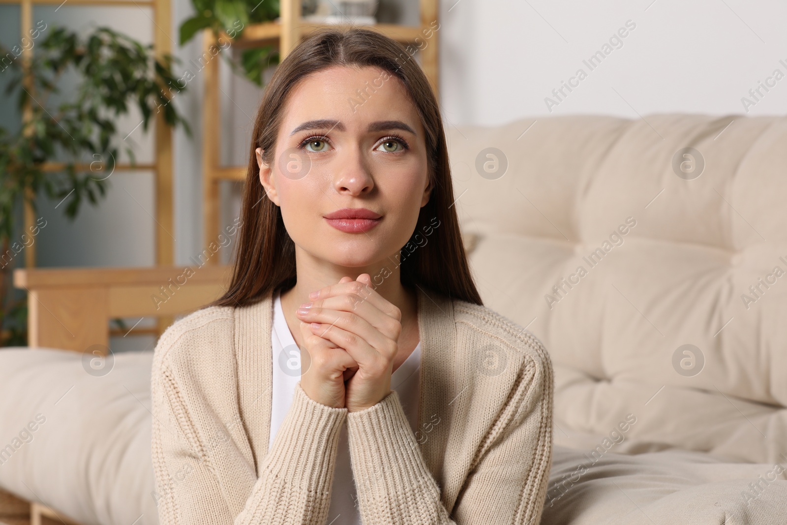 Photo of Woman with clasped hands praying at home