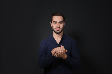 Photo of Man showing BELIEVE gesture in sign language on black background