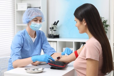 Photo of Laboratory testing. Doctor taking blood sample from patient at white table in hospital