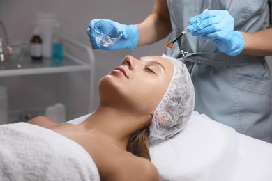 Photo of Cosmetologist applying chemical peel product on client's face in salon