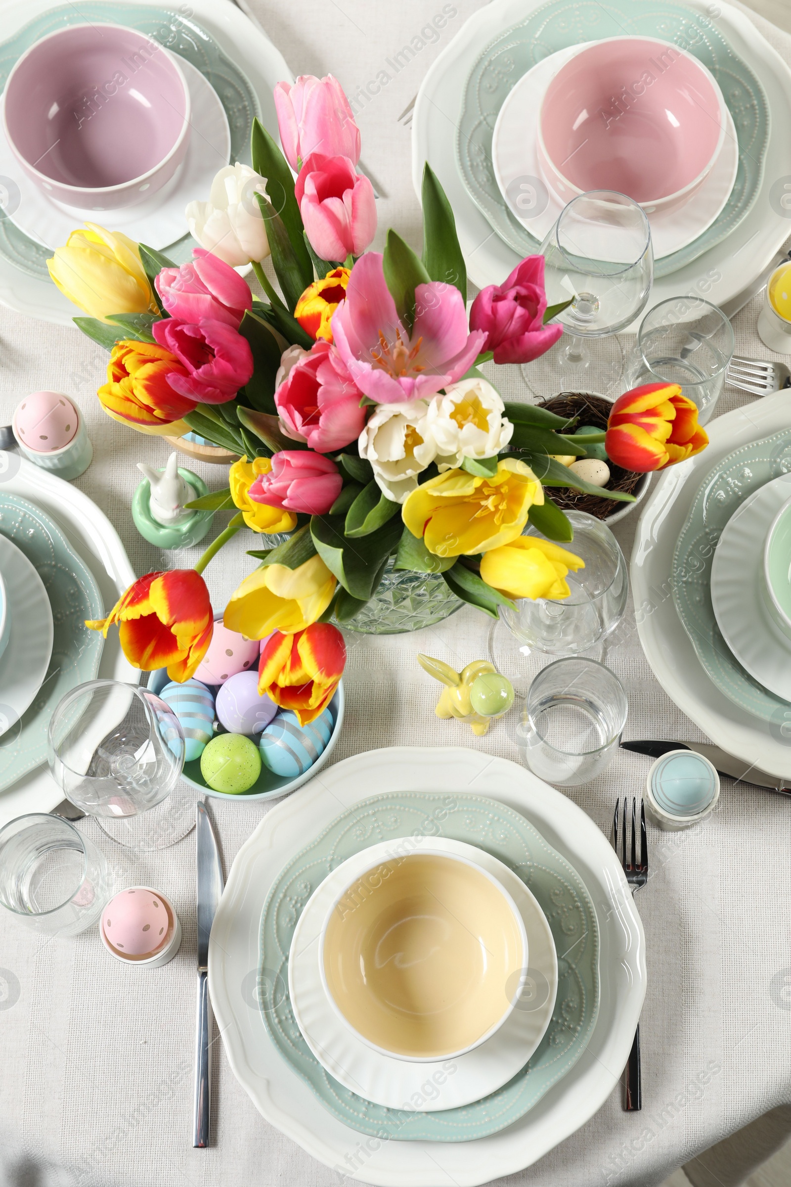 Photo of Festive Easter table setting with beautiful flowers and painted eggs, top view