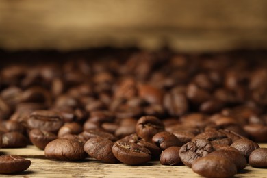 Photo of Many roasted coffee beans on wooden table, closeup