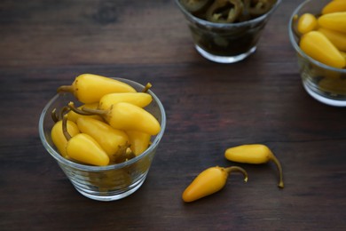 Photo of Pickled green and yellow jalapeno peppers on wooden table