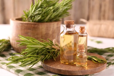 Photo of Essential oil in bottles and rosemary on table