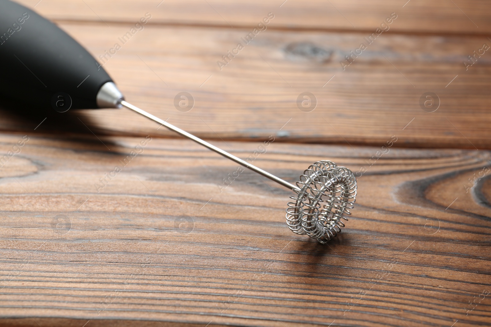 Photo of Black milk frother wand on wooden table, closeup