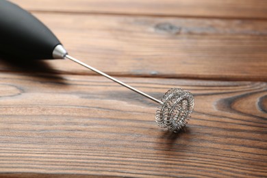 Black milk frother wand on wooden table, closeup