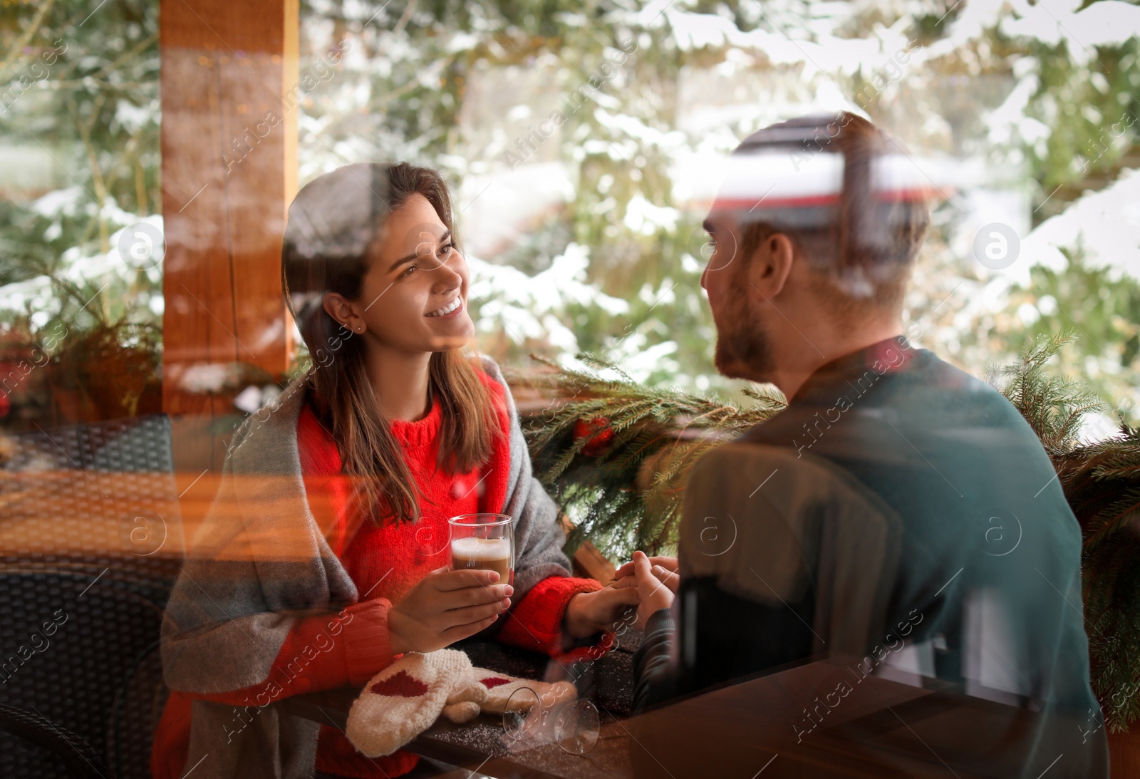 Photo of Lovely couple at table in cafe, view through window. Winter vacation