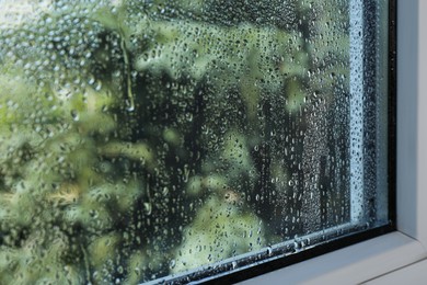 Photo of Window glass with drops of condensate indoors, closeup