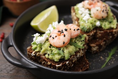 Photo of Delicious sandwiches with guacamole, shrimps and black sesame seeds in serving pan, closeup
