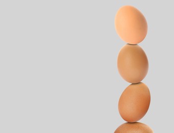 Image of Stacked fresh chicken eggs against light grey background. Space for text