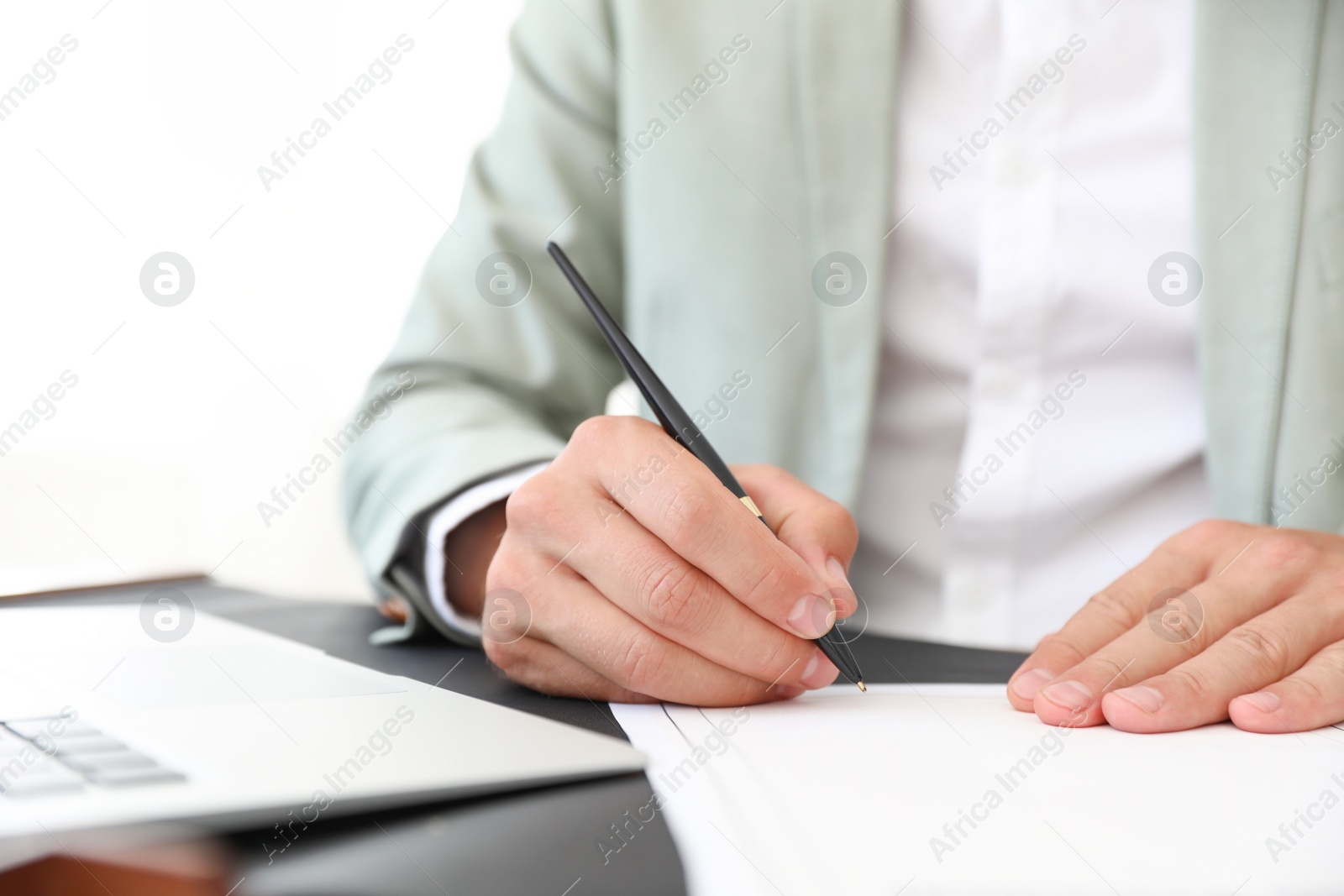 Photo of Male notary signing document at table in office, closeup