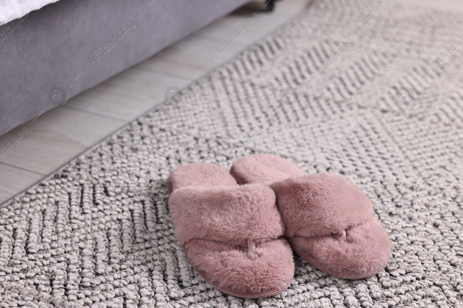 Photo of Pink soft slippers on carpet at home, closeup