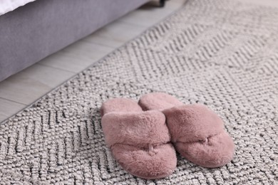 Photo of Pink soft slippers on carpet at home, closeup