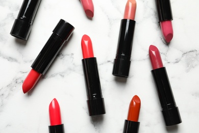 Photo of Different lipsticks on marble background, flat lay