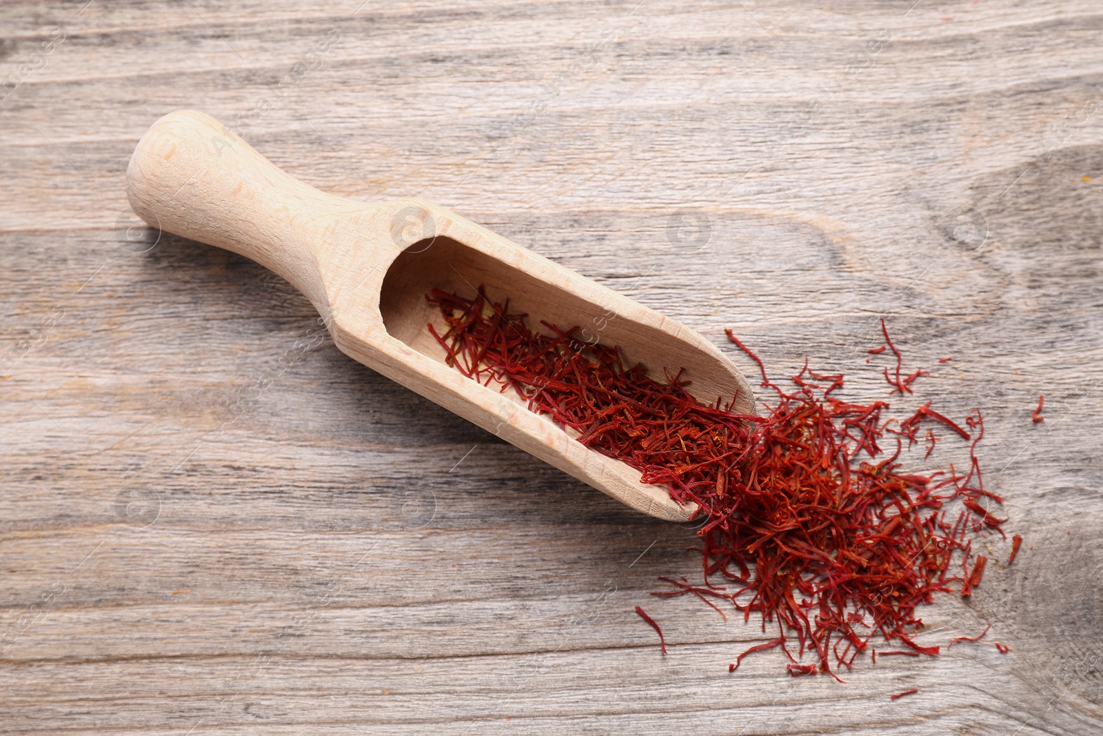 Photo of Aromatic saffron and scoop on wooden table