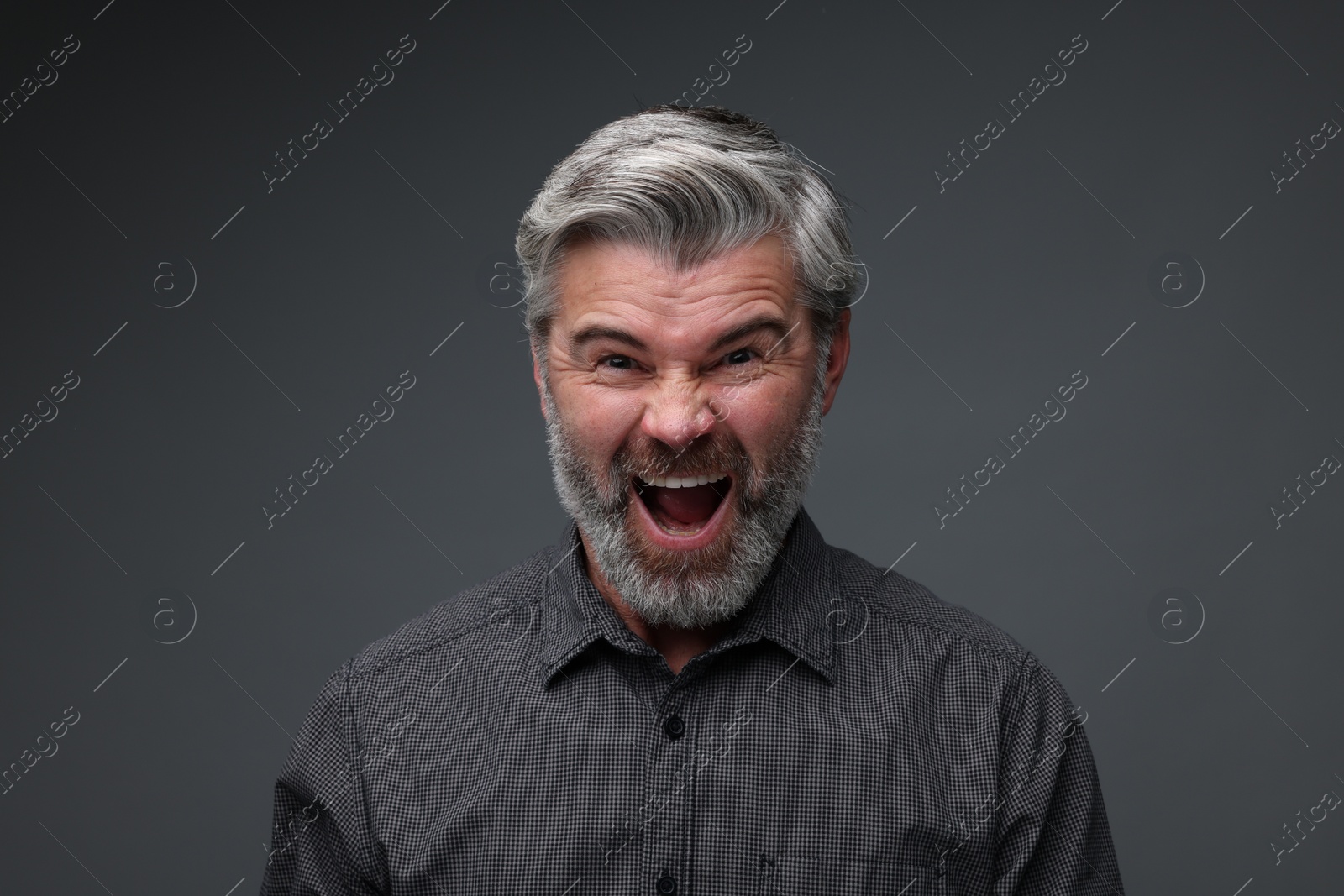 Photo of Personality concept. Emotional man screaming on dark grey background