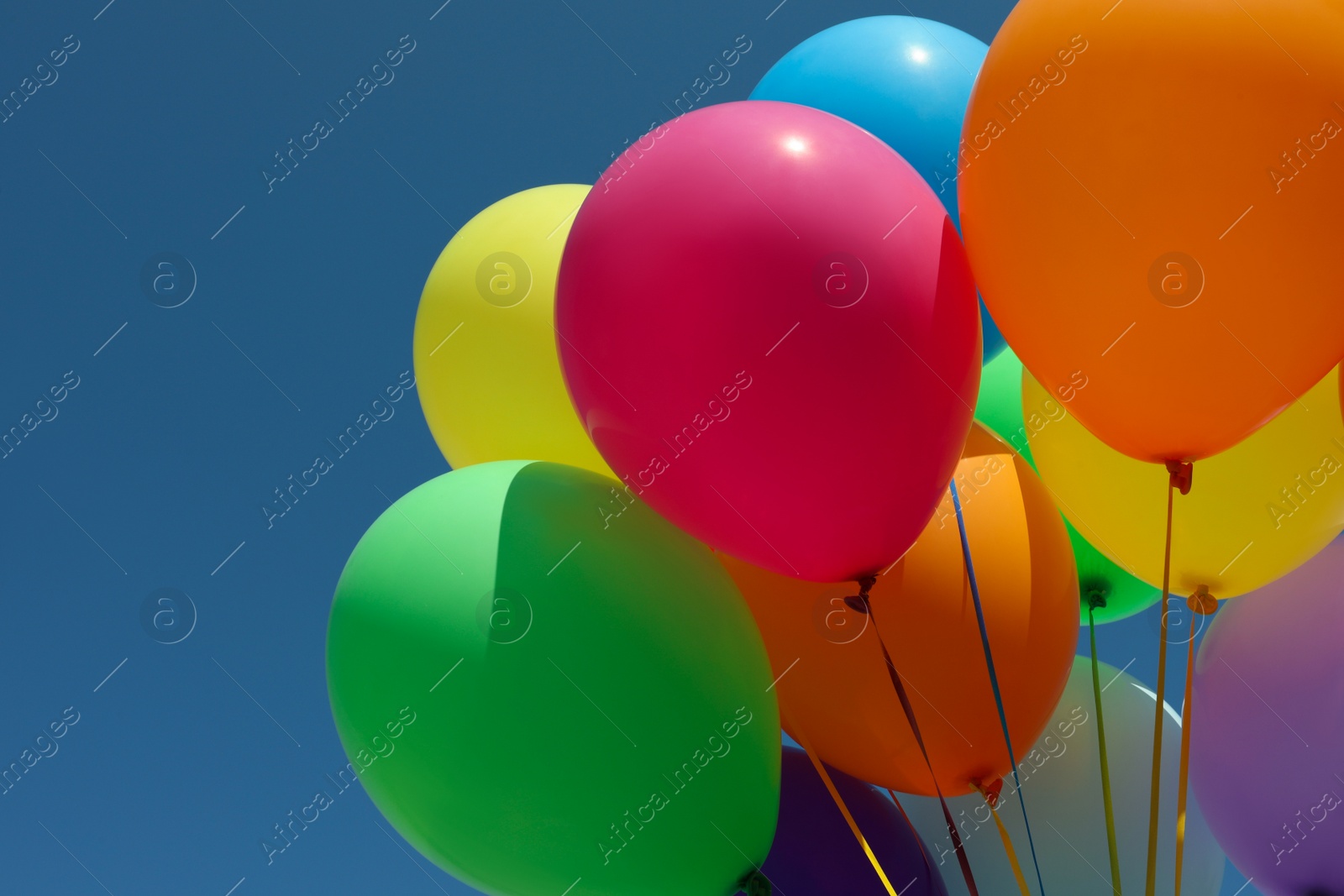 Photo of Bunch of colorful balloons against blue sky, closeup