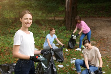 Photo of Group of people with plastic bags collecting garbage in park