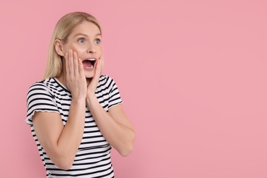 Photo of Portrait of surprised woman on pink background, space for text