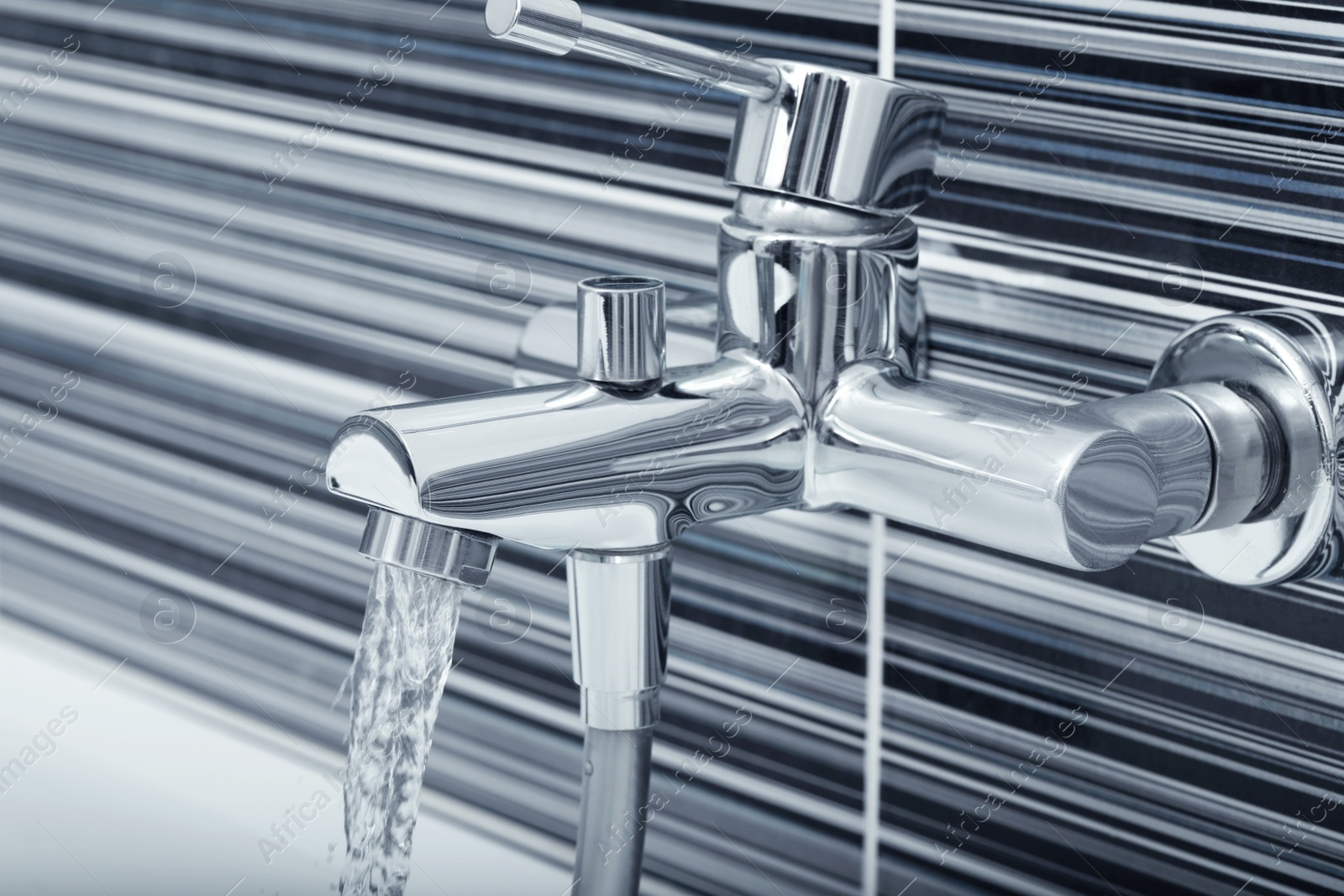 Photo of Water flowing from bath tap installed on black and white wall