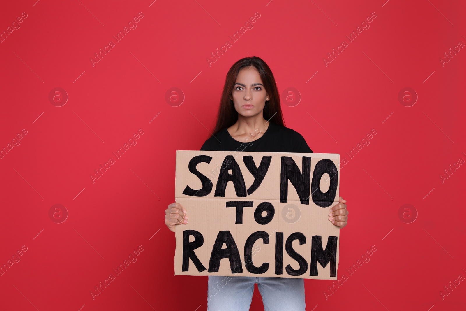 Photo of Young woman holding sign with phrase Say No To Racism on red background