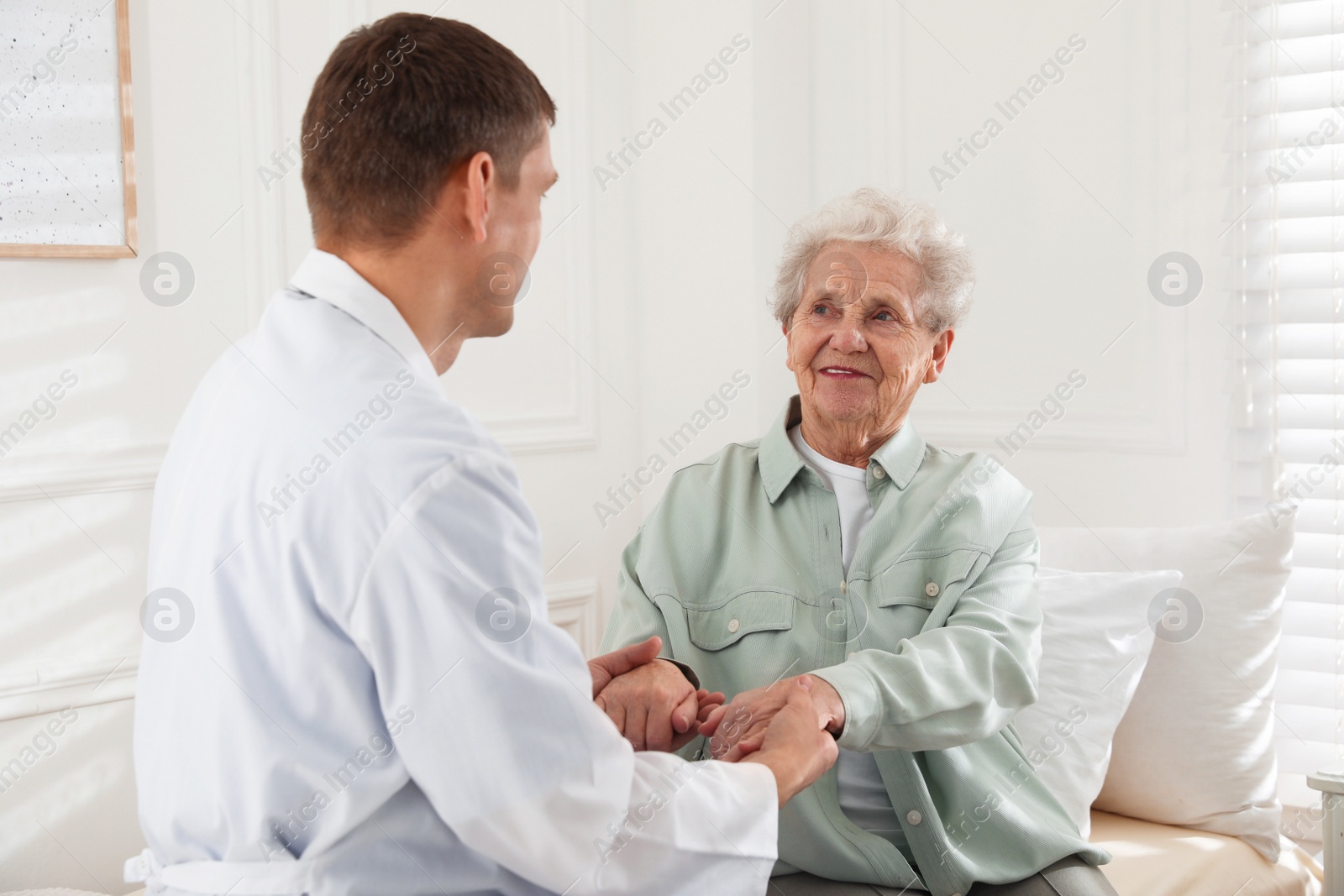 Photo of Caregiver talking to senior woman in living room. Home health care service