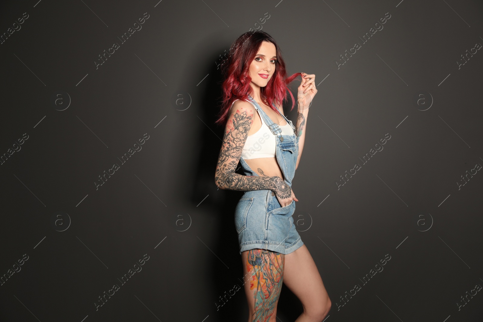 Photo of Beautiful woman with tattoos on body against black background