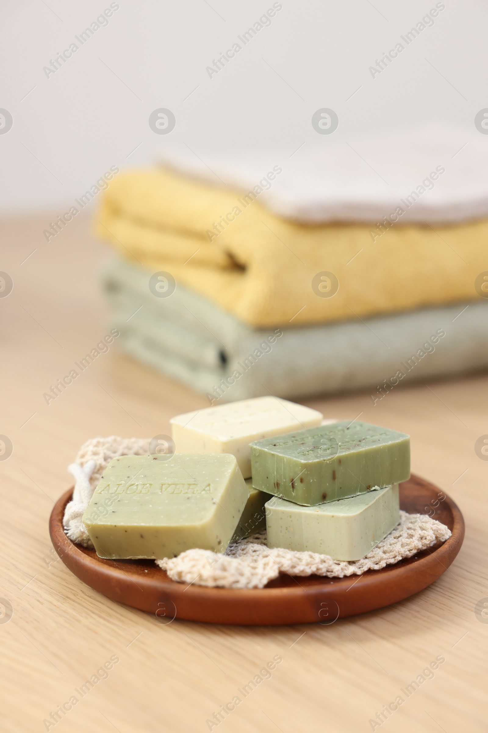 Photo of Tray with soap bars and towels on light wooden table, space for text. Spa therapy