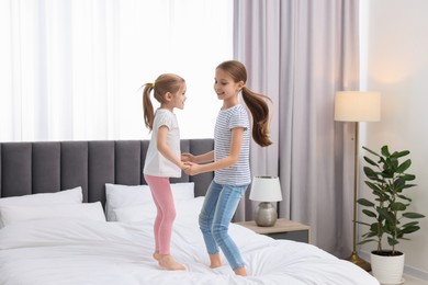 Photo of Cute little sisters having fun together on bed at home
