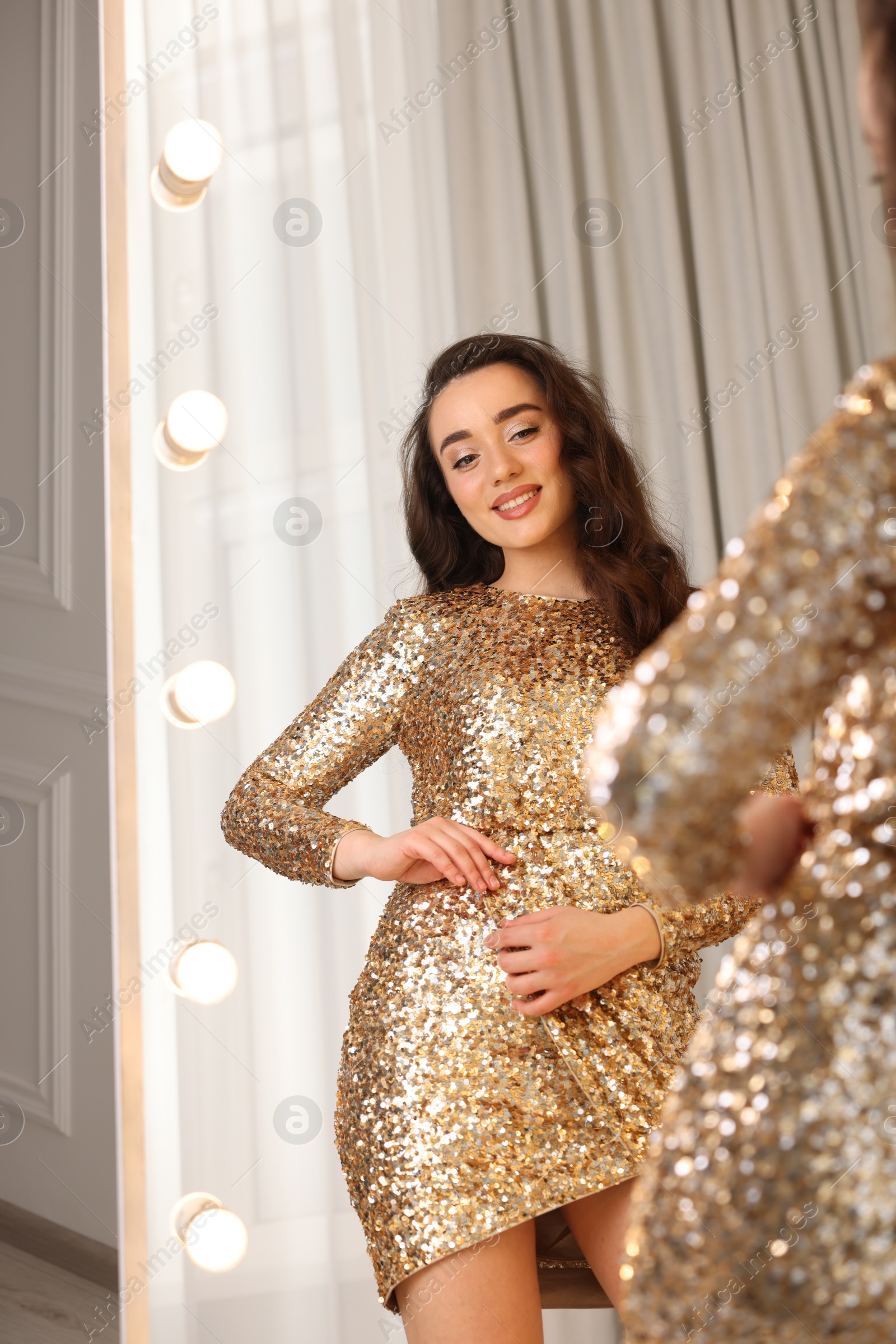 Photo of Beautiful woman in elegant dress near mirror indoors