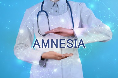 Doctor demonstrating virtual model of word AMNESIA on light blue background, closeup