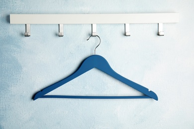 Photo of Rack with empty clothes hanger on color wall. Wardrobe accessory