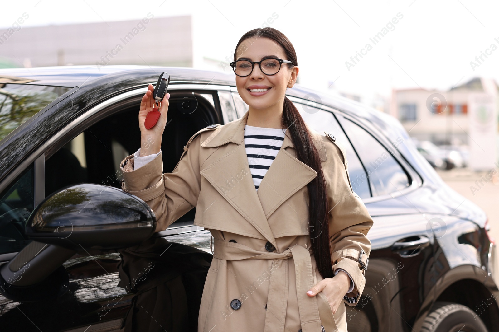 Photo of Woman holding car flip key near her vehicle outdoors