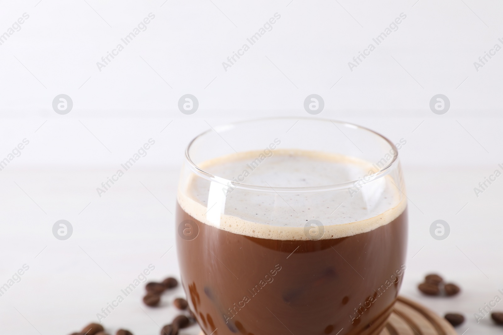 Photo of Refreshing iced coffee with milk in glass on white background, closeup