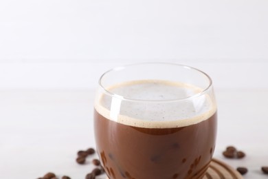Photo of Refreshing iced coffee with milk in glass on white background, closeup