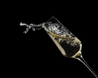 Glass of fizzy champagne on black background, closeup