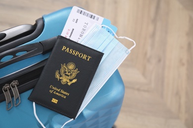 Passport, protective mask and tickets on blue suitcase. Travel during quarantine